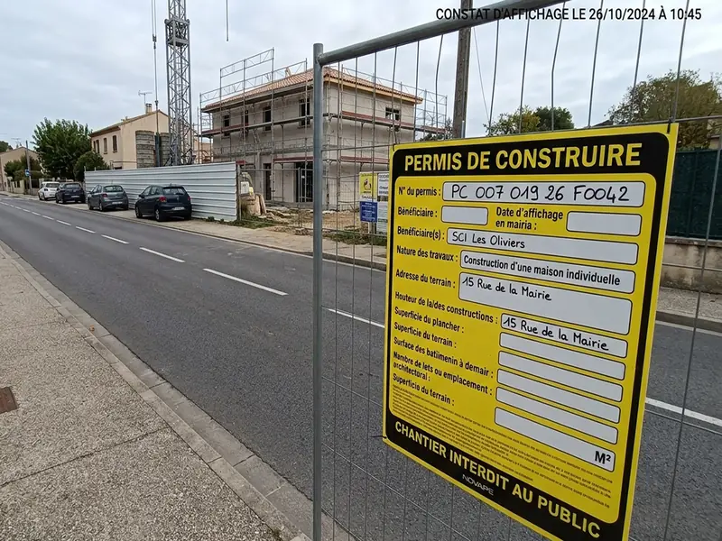 Panneau de permis de construire affiché sur la clôture d'un chantier, en bord de voie publique