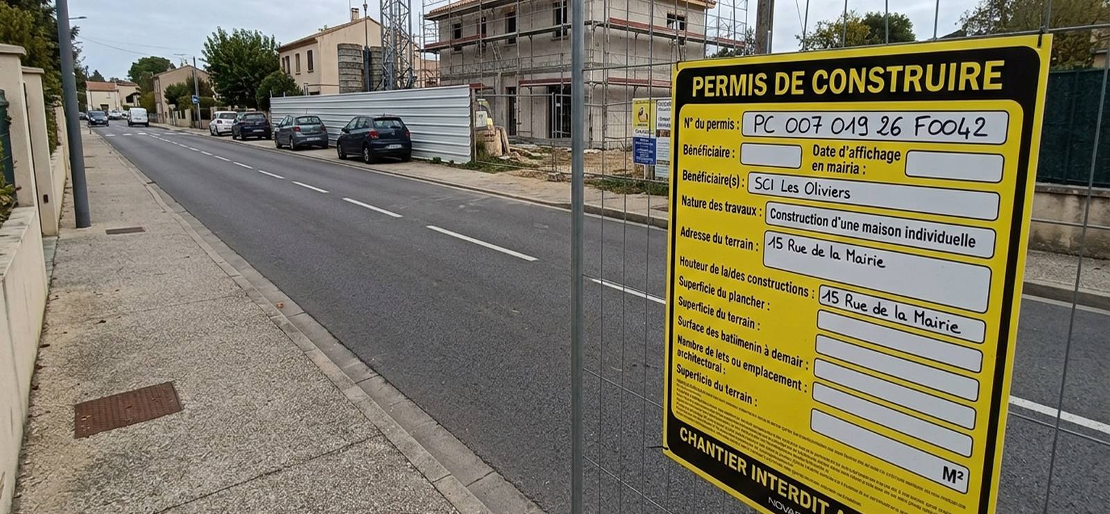 Panneau de permis de construire affiché sur la clôture d'un chantier, en bord de voie publique